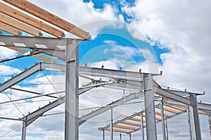 Metal frame of the new building against the blue sky with clouds.