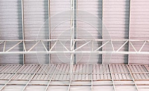 The metal frame of the roof structure with the roof tile covers the large warehouse