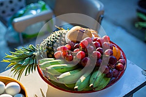 Metal fruit bowl on a wooden surface. Close. Bananas, oranges and apples.