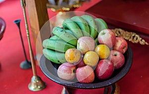 Metal fruit bowl on a wooden surface. Close. Bananas, oranges and apples. Mix of fresh apple,banana,orange, in a basket.