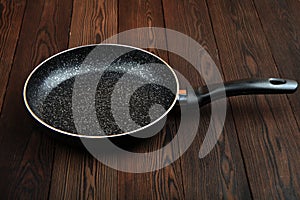 Metal frying pan: Ceramic coating with non-stick coating: Kitchen utensils On a wooden background: Cooking for chefs in the