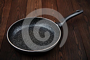 Metal frying pan: Ceramic coating with non-stick coating: Kitchen utensils On a wooden background: Cooking for chefs in the