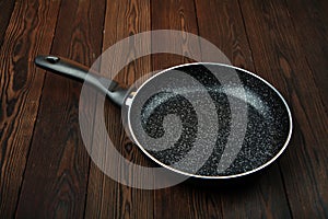 Metal frying pan: Ceramic coating with non-stick coating: Kitchen utensils On a wooden background: Cooking for chefs in the