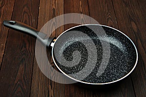 Metal frying pan: Ceramic coating with non-stick coating: Kitchen utensils On a wooden background: Cooking for chefs in the