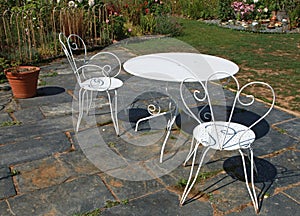 Metal garden furniture on a slate terrace in a landscaped park