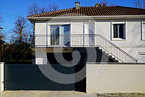 Metal gate grey fence on suburb street storey house with outdoors stairs