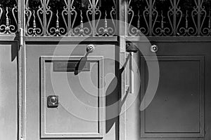 Metal gates with ornate lattice and rectangular frame with lock. Shadows from doorknobs. Nameplate `Pull` in French language.
