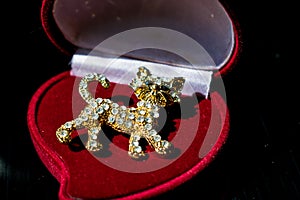 Metal Golden brooch in the form of a kitten or a tiger cub with white stones, rhinestones. On a black glossy, reflective backgroun