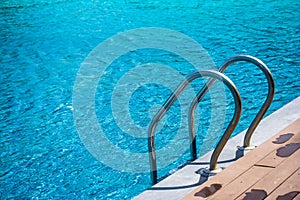 Metal grab bar ladder in blue water swimming pool.