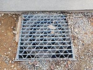 metal grate or drain for sewer on ground with rocks