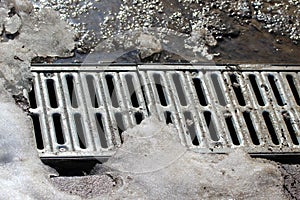 Metal grate of water drainage under the melting snow