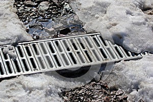 Metal grate of water drainage under the melting snow