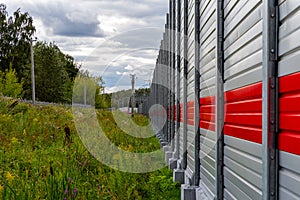 Metal gray fence with red stripe, thick pre-rain clouds and summer colorful landscape