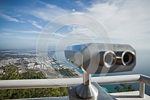 Metal grey coin operated telescope isolated at beautiful summer panoramic view at cityscape