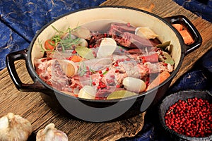 Metal grill pan with raw meat, vegetables and spices on a wooden board background