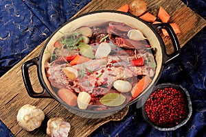 Metal grill pan with raw meat, vegetables and spices on a wooden board background