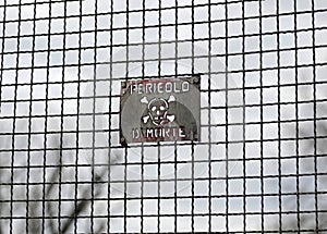 metal grille with dark tones and a sign which in Italian means Danger of Death photo