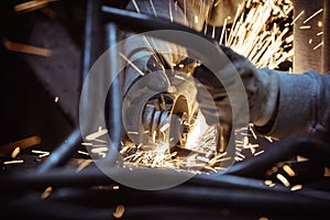 Metal grinding on steel pipe with flash of sparks and loops of metal pipe close up