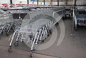 Metal grocery carts stand in a store parking bay