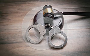 Metal handcuffs and judge gavel on the wooden background