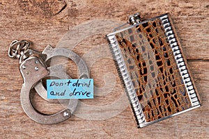 Metal handcuffs, paper message, hip flask.