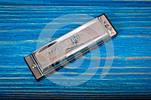 A metal harmonica with ten holes, a wind instrument, photographed on a wooden surface