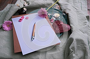 Metal heart and gerbera, writing materials on the table, near a candle and decorations