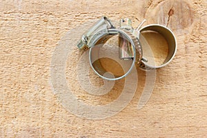 Metal hose clamps hardware tools with copy space isolated on wooden background closeup.