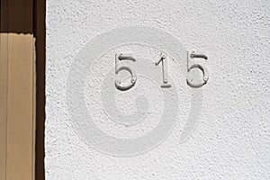 Metal house number 515 on a white stucco wall background