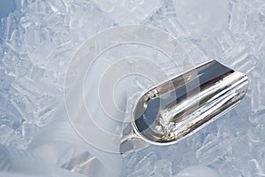 Metal ice scoop and plastic cup on the ice in bucket