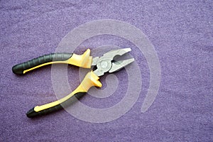 Metal, iron pliers with rubberized yellow-black handles