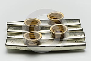 Metal kazoos on a white reflective surface
