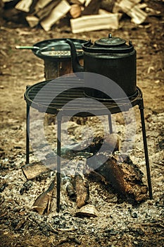 A metal kettle, black with soot, stands on a metal grate over the fire. Tourist lunch.