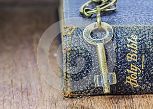 The metal key on holy bible on wooden table