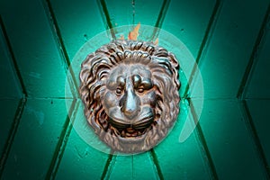 The Metal knocker like a lion`s head in a green doorway