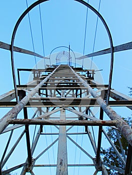 Metal ladde with blue white paint on galvanized surface, rusty places. Broken safety frame around main beams.