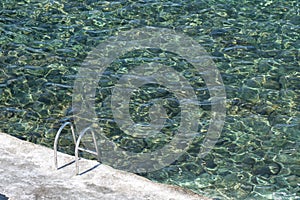 Metal ladder leading into a clear seawater pool