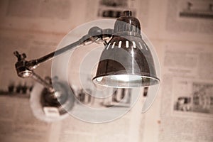 Metal lamp hanging from a wall coated in newspaper