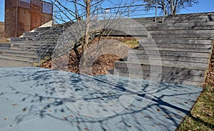 Metal lattice floor terrace under a wooden staircase that serves as a bench or auditorium yard in the park on the promenade. . squ