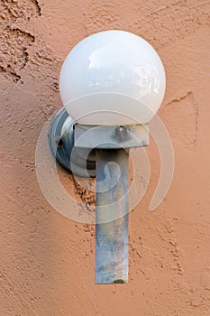 Metal light attached to side of house home or building in the downtown city in late afternoon shade with orange exterior
