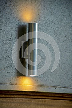 Metal light beam with orange emitting from top and bottom on interior wall for decorative purposes