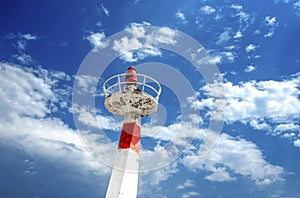 Metal lighthouse under cloudscape sky.