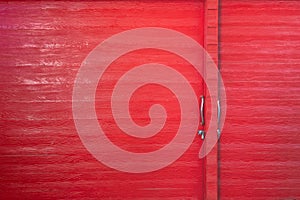 Metal lock and door handle on the red wooden door. Abstract red wood planks background wall texture. Wooden texture red colour for