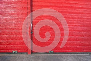 Metal lock and door handle on the red wooden door. Abstract red wood planks background wall texture. Wooden texture red colour for