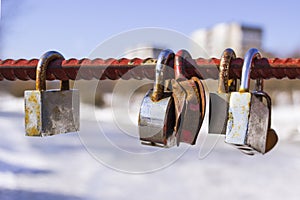 Metal lock hangs on thick rope. The lock hangs on the armature on the bridge. Symbol of Love