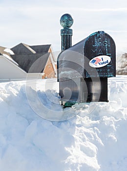 USPS metal mailbox buried in snow drift I voted sticker for vote by mail photo