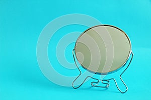 Metal make up mirror, blue background, free copy space, selective focus