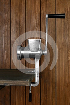 Metal manual meat grinder on table against wooden background