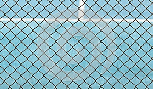 Metal Mesh fence on blurred background of blue tennis hard court