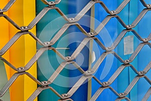 Metal mesh fencing on the background of a multi-colored wooden fence